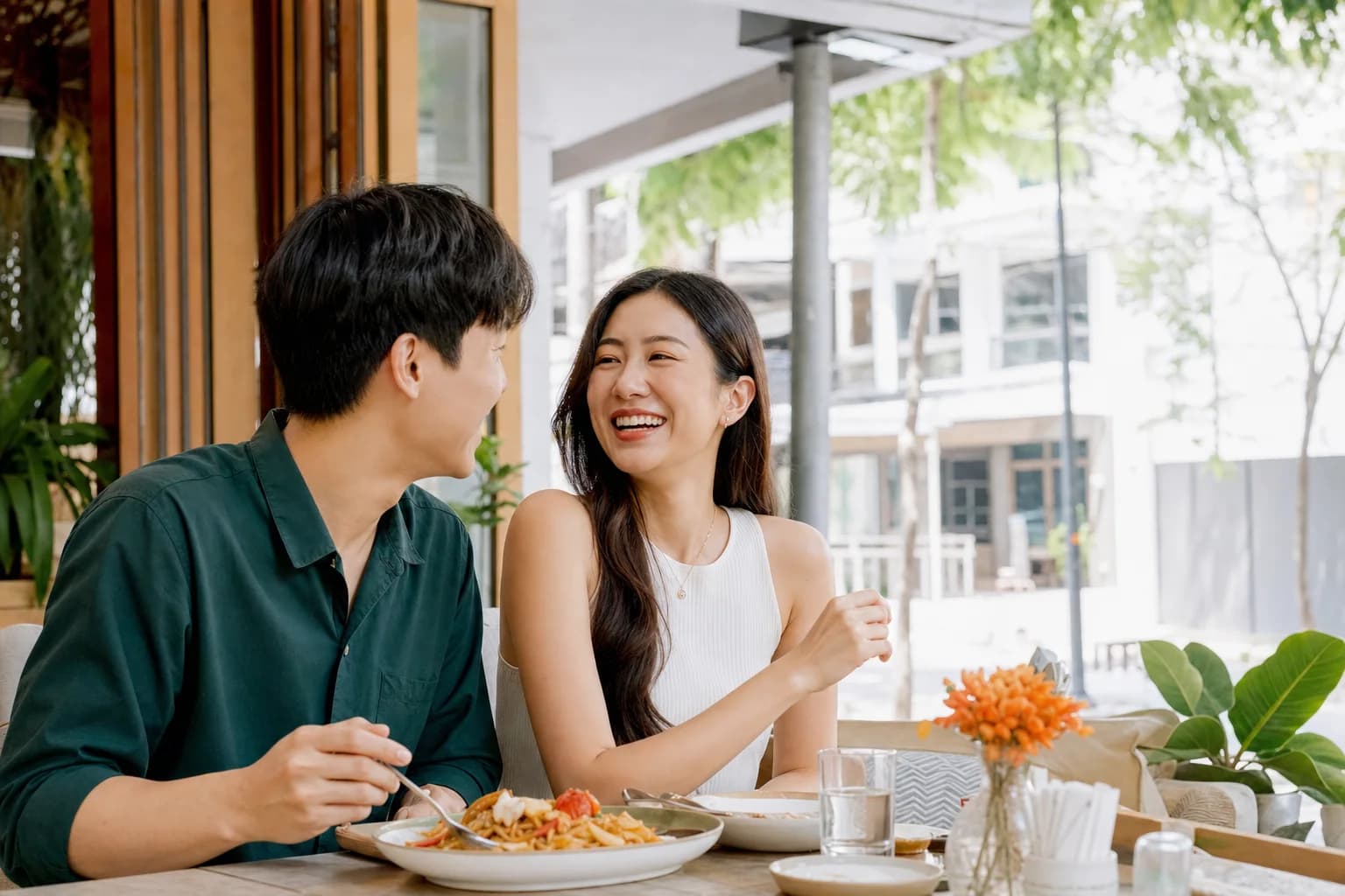 Two adults laughing together during a daytime date at a Bangkok cafe